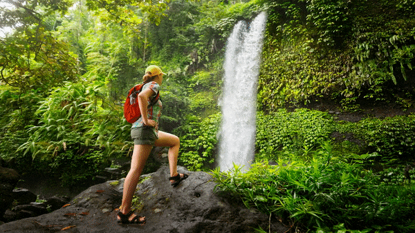Still image of woman looking at waterfall, with the water moving