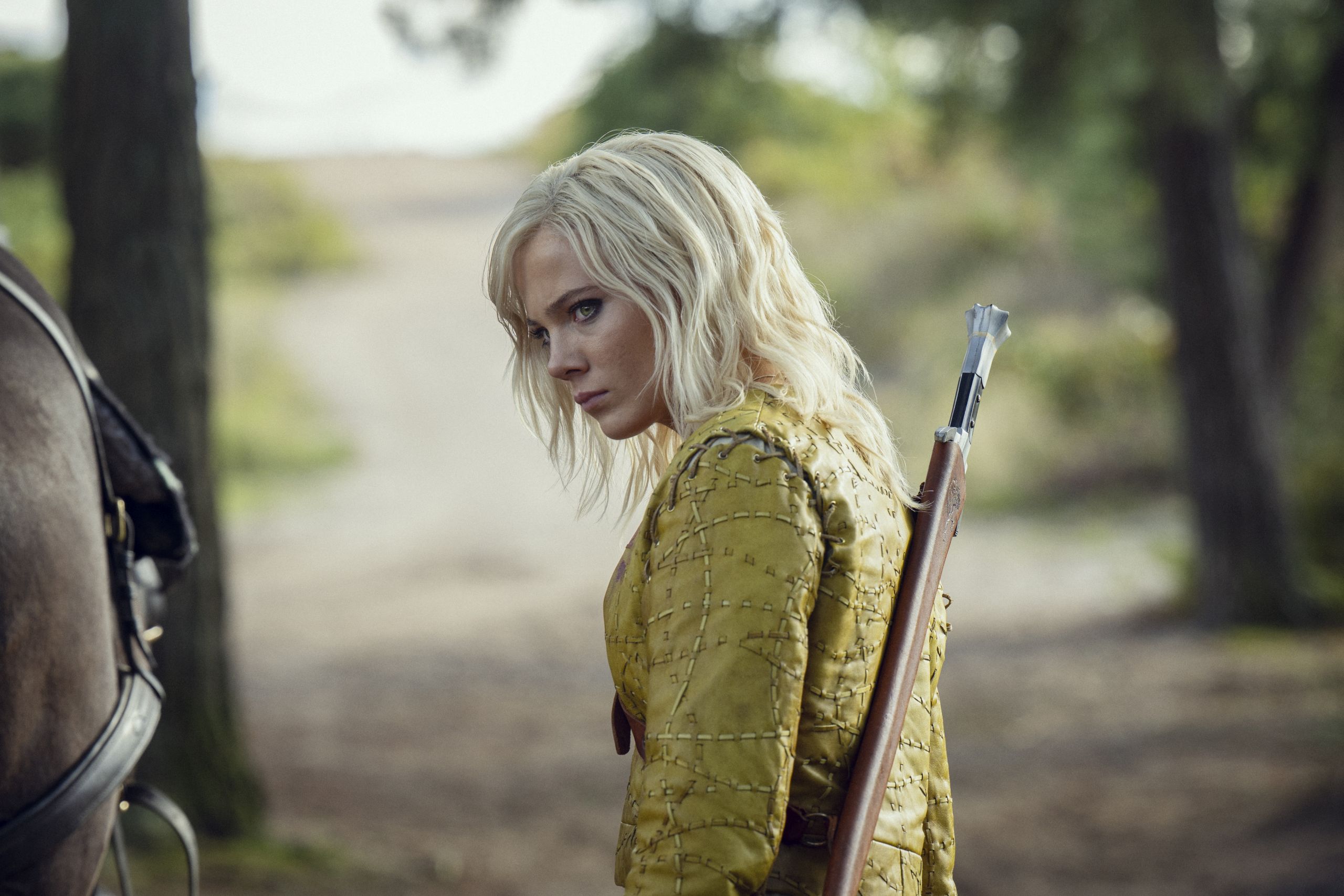 Ciri looks over her shoulder with a sword on her back