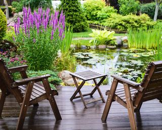Garden furniture on a deck next to a garden pond