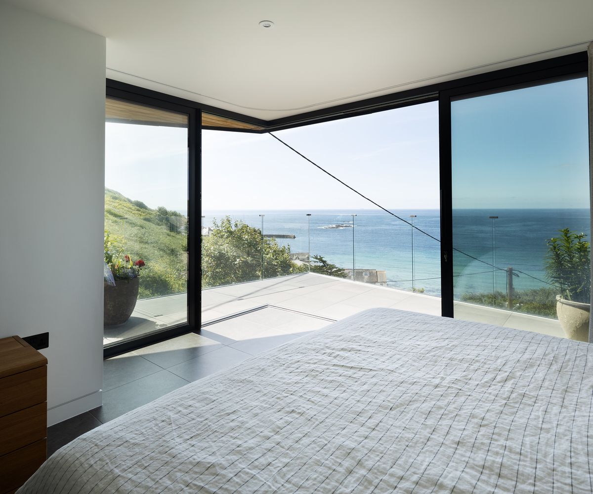 Bedroom with cantilever glass sliding doors which open out onto a private terrace with a sea view