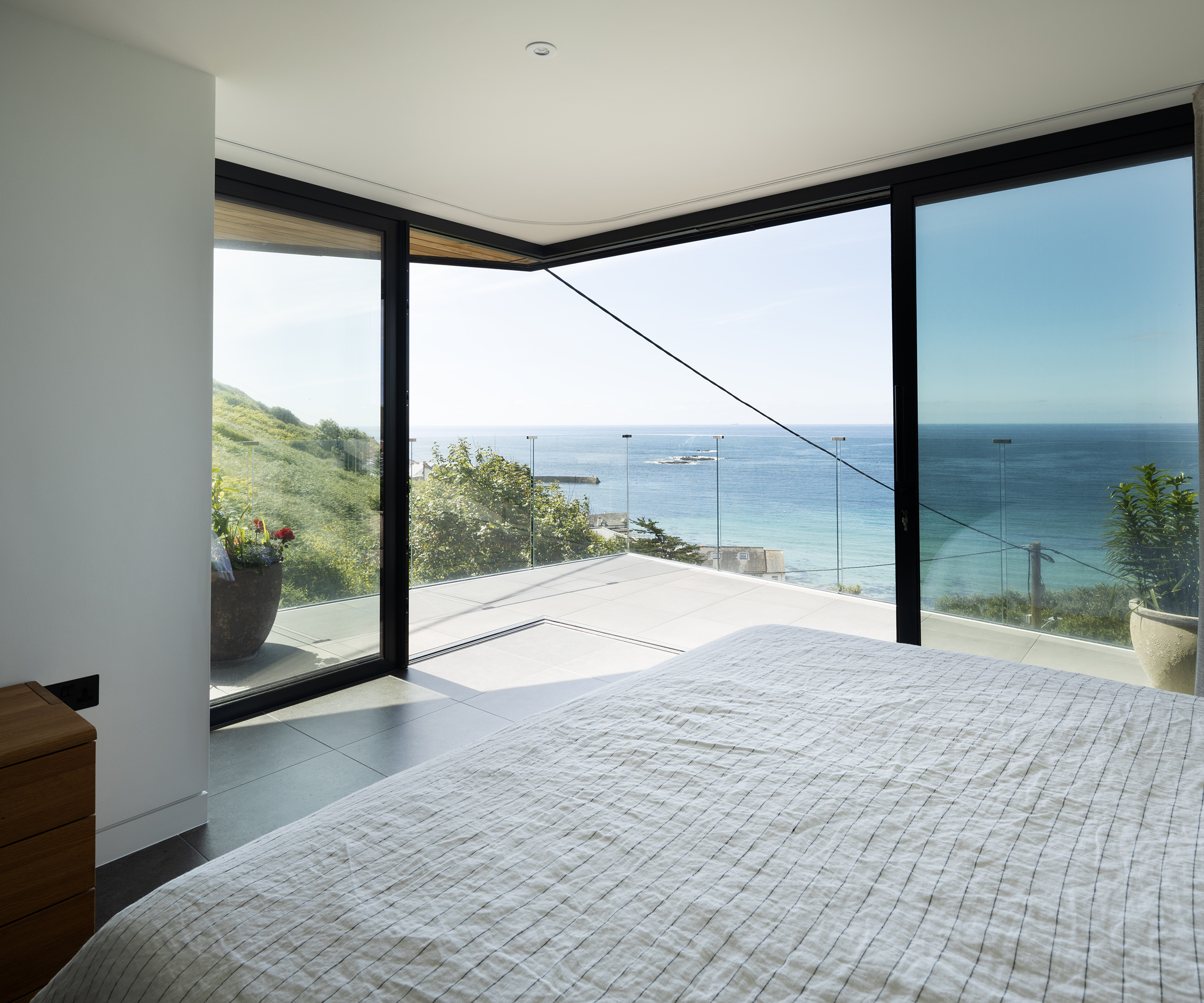 Bedroom with cantilever glass sliding doors which open out onto a private terrace with a sea view