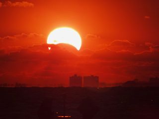 Photographer James Currie captured this view of the sunrise partial solar eclipse over Norfolk, Va., on Nov. 3, 2013 during a rare hybrid solar eclipse. 'This was the first time I got to see a solar eclipse!' Currie told SPACE.com.