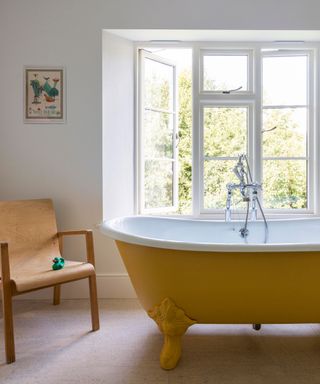 Traditional bathroom with a roll top bath tub painted in a bright yellow paint color