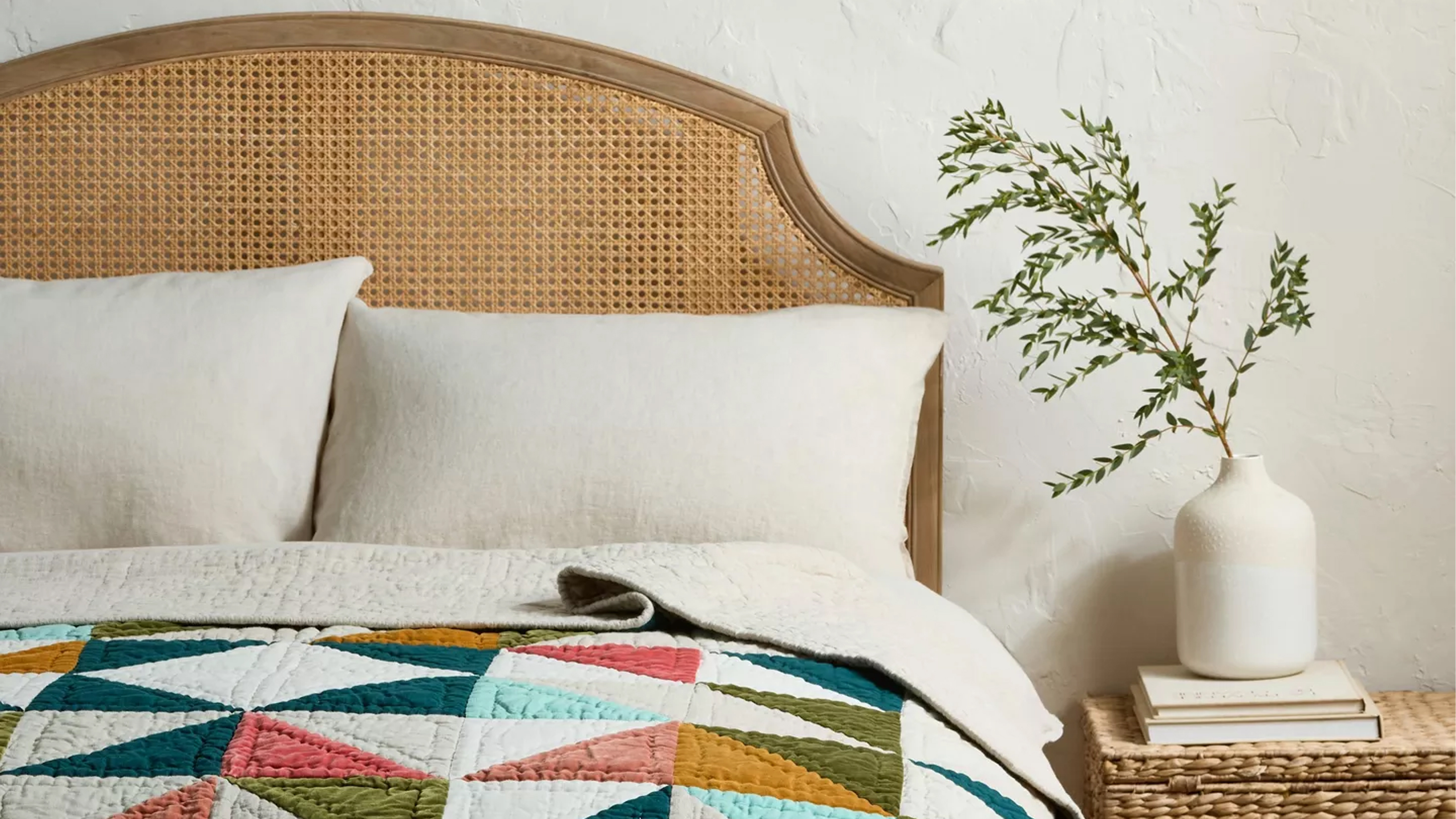 John Lewis multicoloured patchwork quilt on a bed with a curved rattan headboard