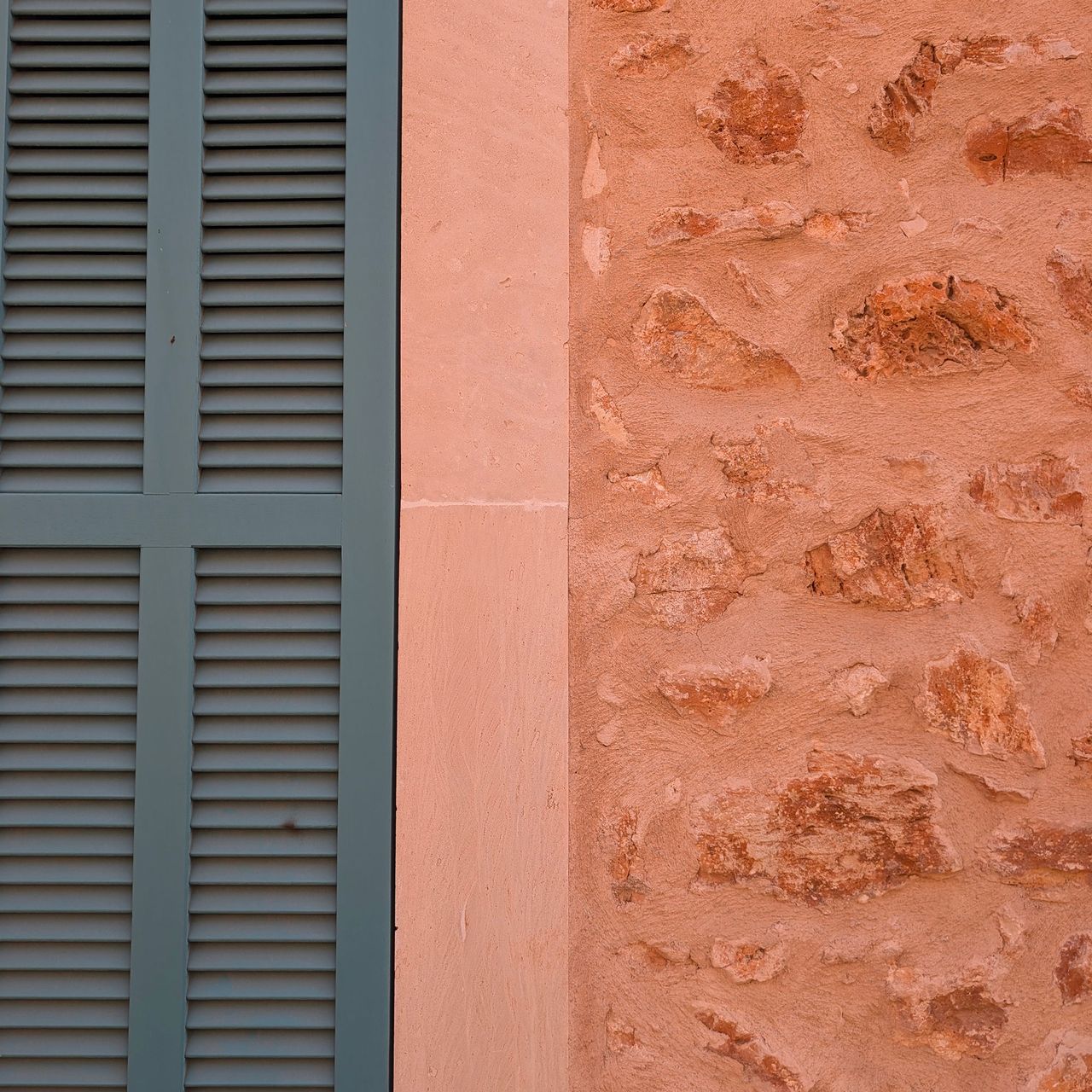 Deep green/blue external shutters alongside terracotta coloured wall