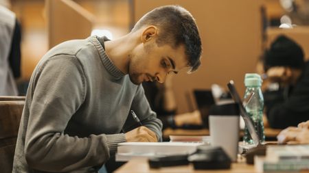 A college student looks focused as he does schoolwork in the library.