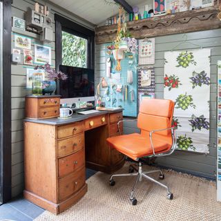 Garden office with desk and desk chair, wall panelling, hanging planters and pegboard