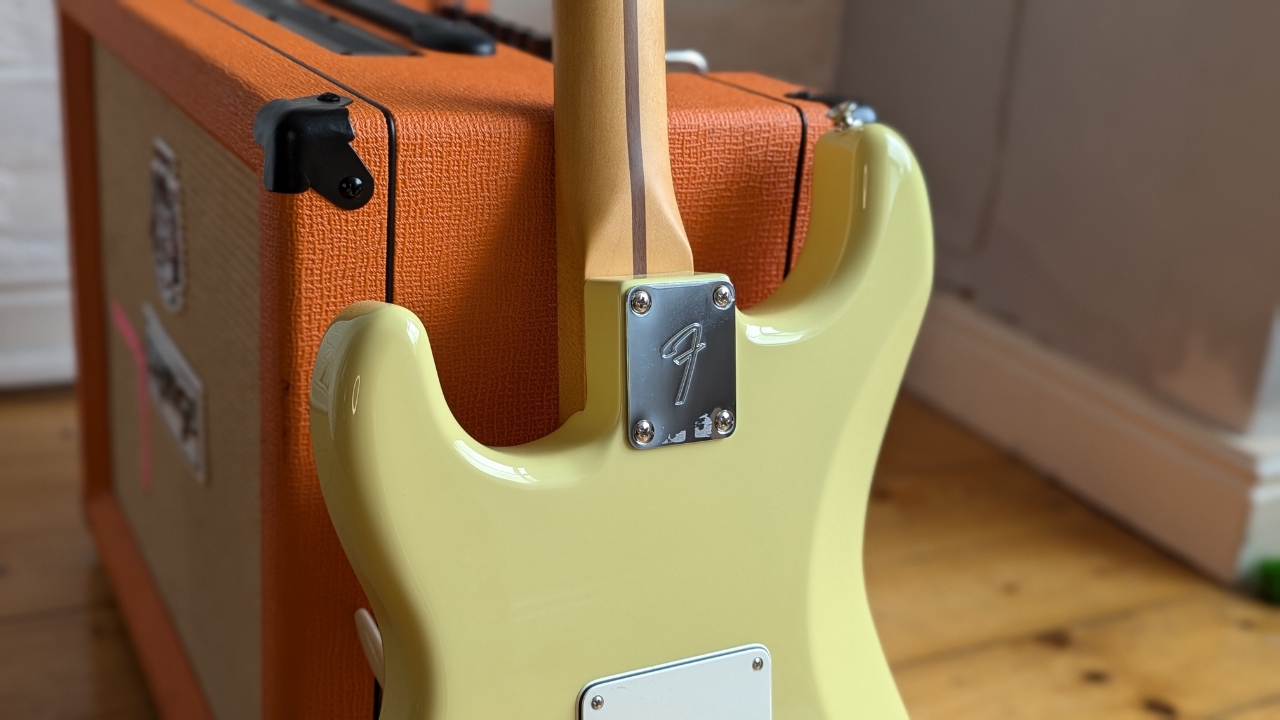 The neck heel of a Fender Player II Stratocaster leaning against a guitar amplifier