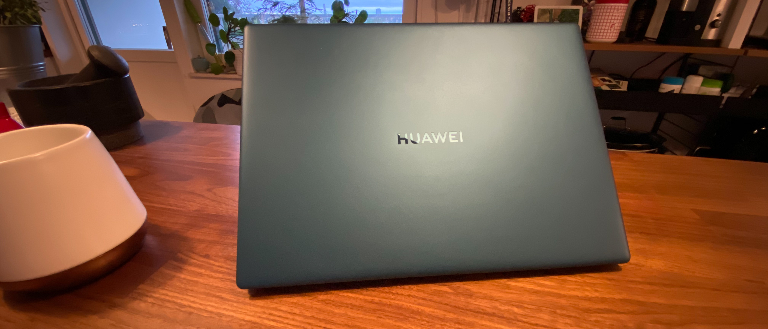 Huawei MateBook X (2020) i den skogsgröna färgen på ett bord jämte en kaffekopp.