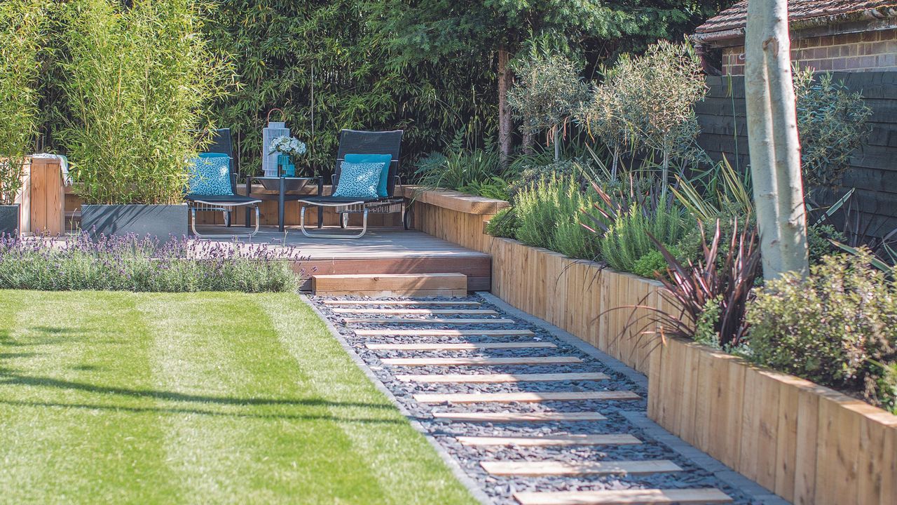 Gravel and patio garden edging path next to lawn and raised wooden planters