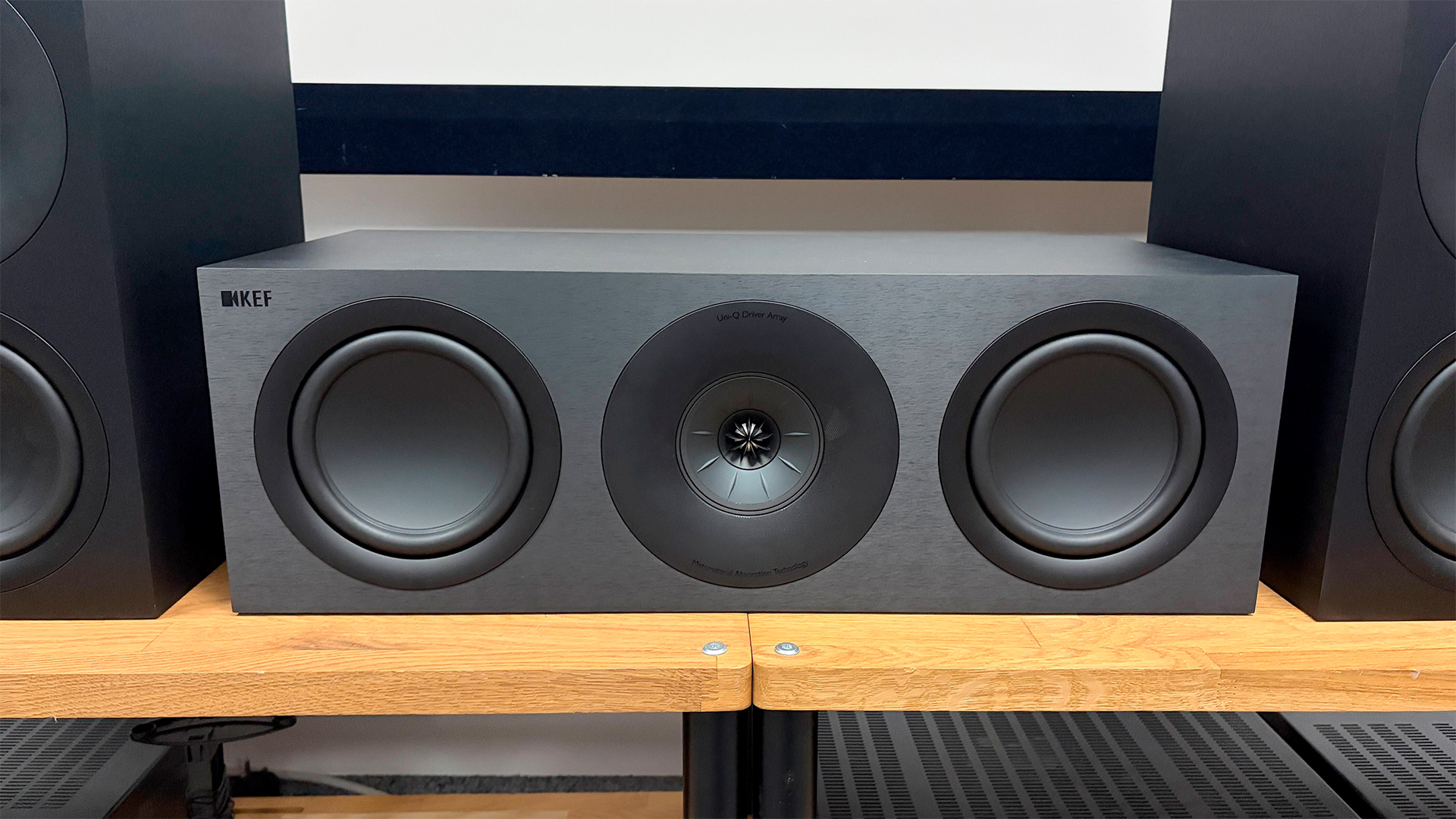 KEF Q Concerto Meta 5.1 speaker package on wooden AV benches focus on centre speaker