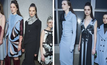 Models waiting in line for a fashion show to start, wearing elegant coats and vintage-looking suits in light blue, covered with tapestry-inspired prints and black lace, from the Antonio Marras A/W 2015 collection.