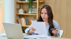 A woman appears shocked while reading a credit card statement