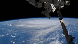 a tremendous typhoon is seen on Earth's horizon from the vantage point of a space station