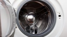 Open the door of white washing machine with a metal drum