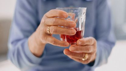 Person holding a glass containing pomegranate juice