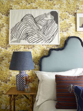 Guest bedroom with yellow wallpaper, table lamp and artwork