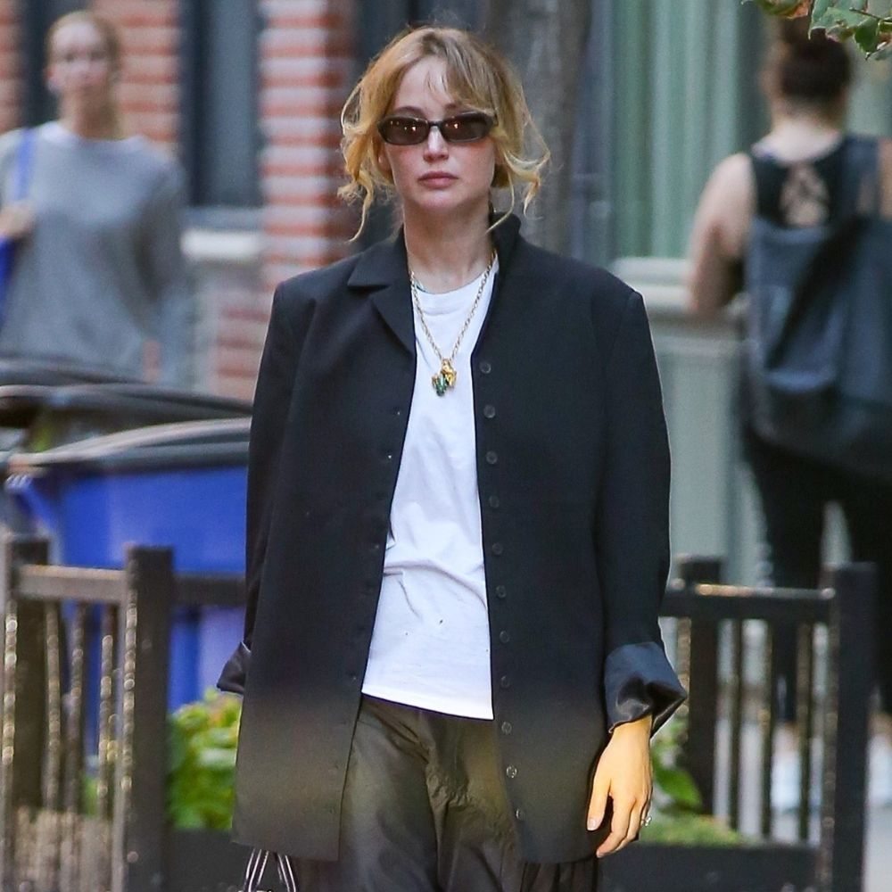 Jennifer Lawrence walks through New York wearing a black midiskirt with black ballet flats and a black single breasted jacket.