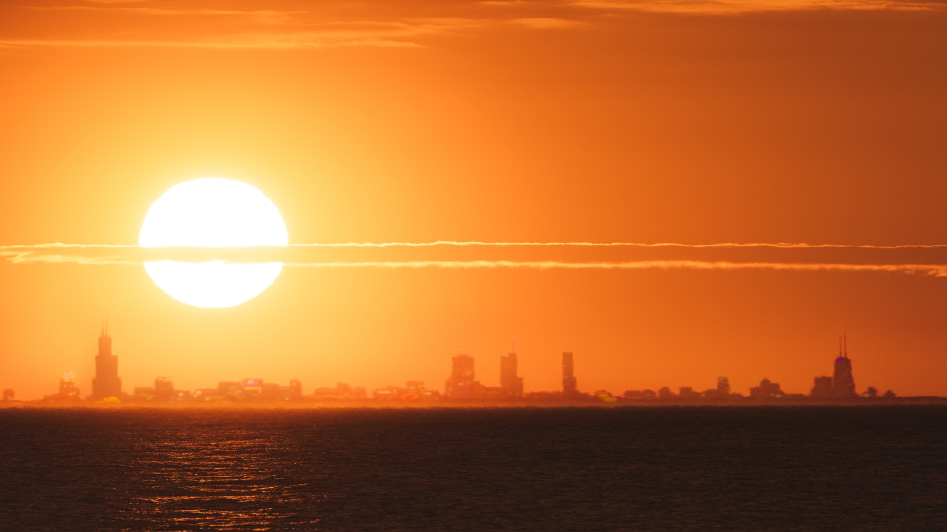 a bright sun in an orange-and-red sky above a city skyline