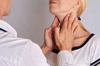 A woman gets her thyroid checked at by a doctor.