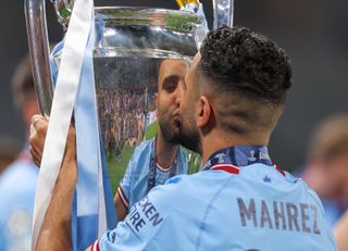 Riyad Mahrez kisses the Champions League trophy after Manchester City's treble triumph in 2023.