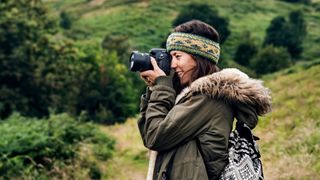 Woman taking pictures with camera on hiking trip