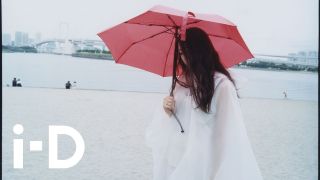 Woman holding red umbrella on a city beach
