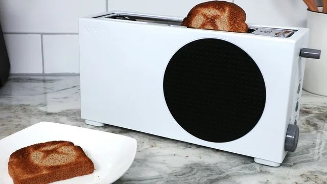 The Xbox Series S Toaster on a kitchen countertop with a slice of toast.