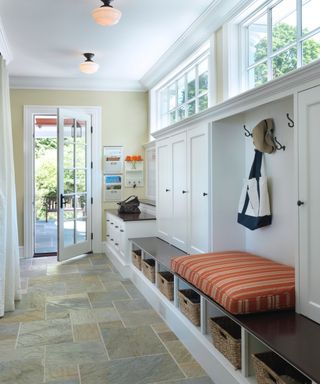 mudroom with built in storage, cupboards, cushion bench, wall hooks and stone flooring - Kelly Taylor