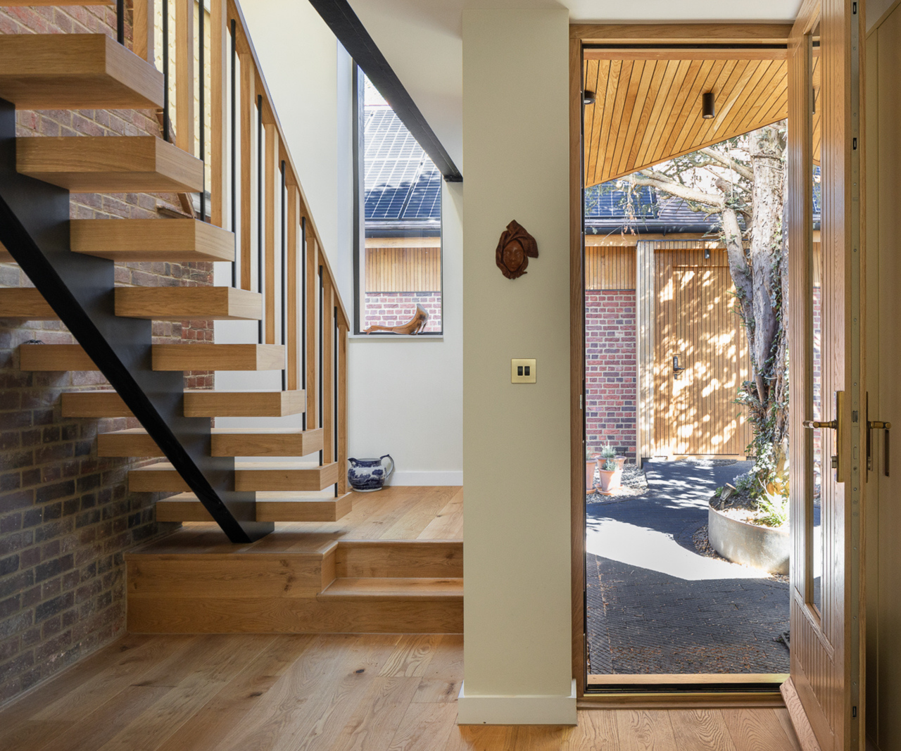 Entrance with front door open to the right and wooden ghost stairs to the left with vertical window behind
