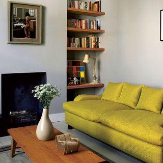 living room with wooden shelves and yellow sofaset with cushions