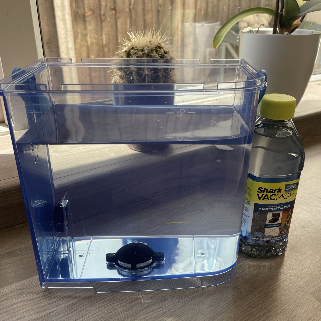 Clean water tank of the Shark UV reveal vacuum mop, with a bottle of VacMop solution next to it