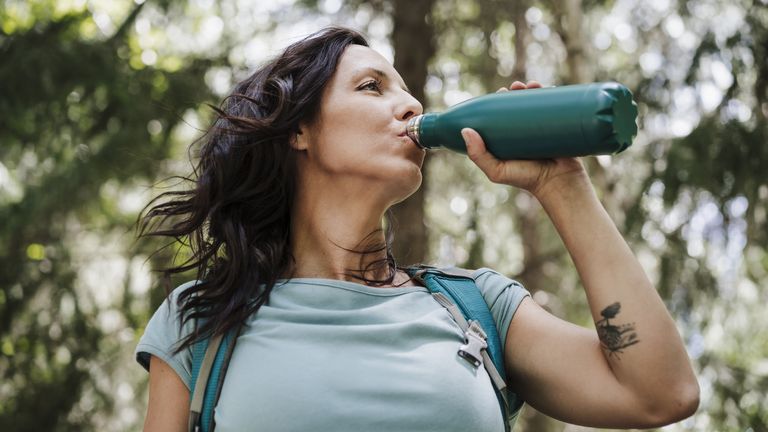 Best water bottles for hiking: A woman drinking from a water bottle for hiking