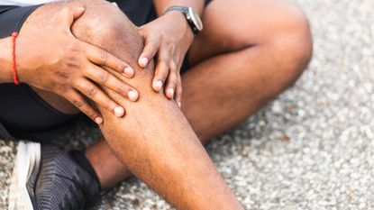 Is running bad for your knees? Image shows runner holding kneee