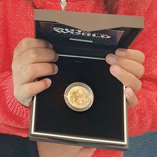 a golden coin in a black case is held up for display