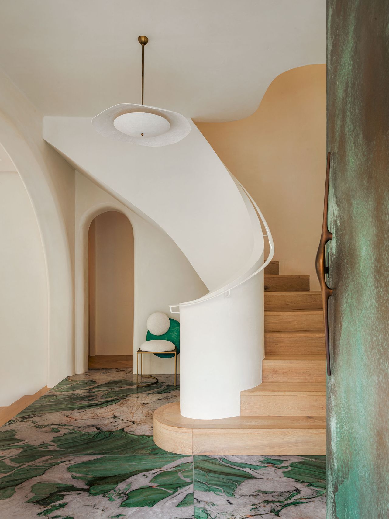 Entry way with white and light wood spiral staircase and green and grey marble effect floor tiles, with a large green metal front door.