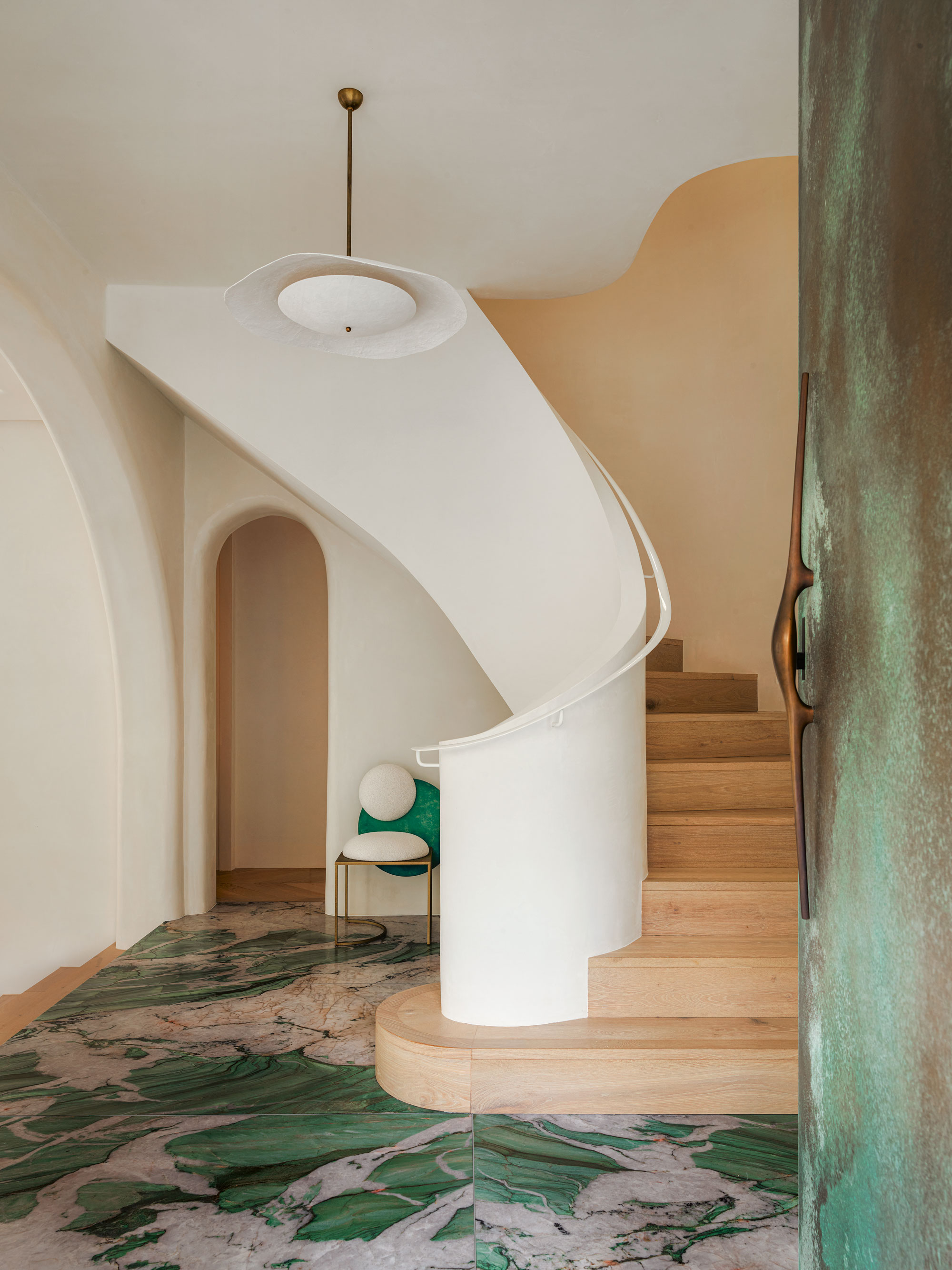 Entry way with white and light wood spiral staircase and green and grey marble effect floor tiles, with a large green metal front door.