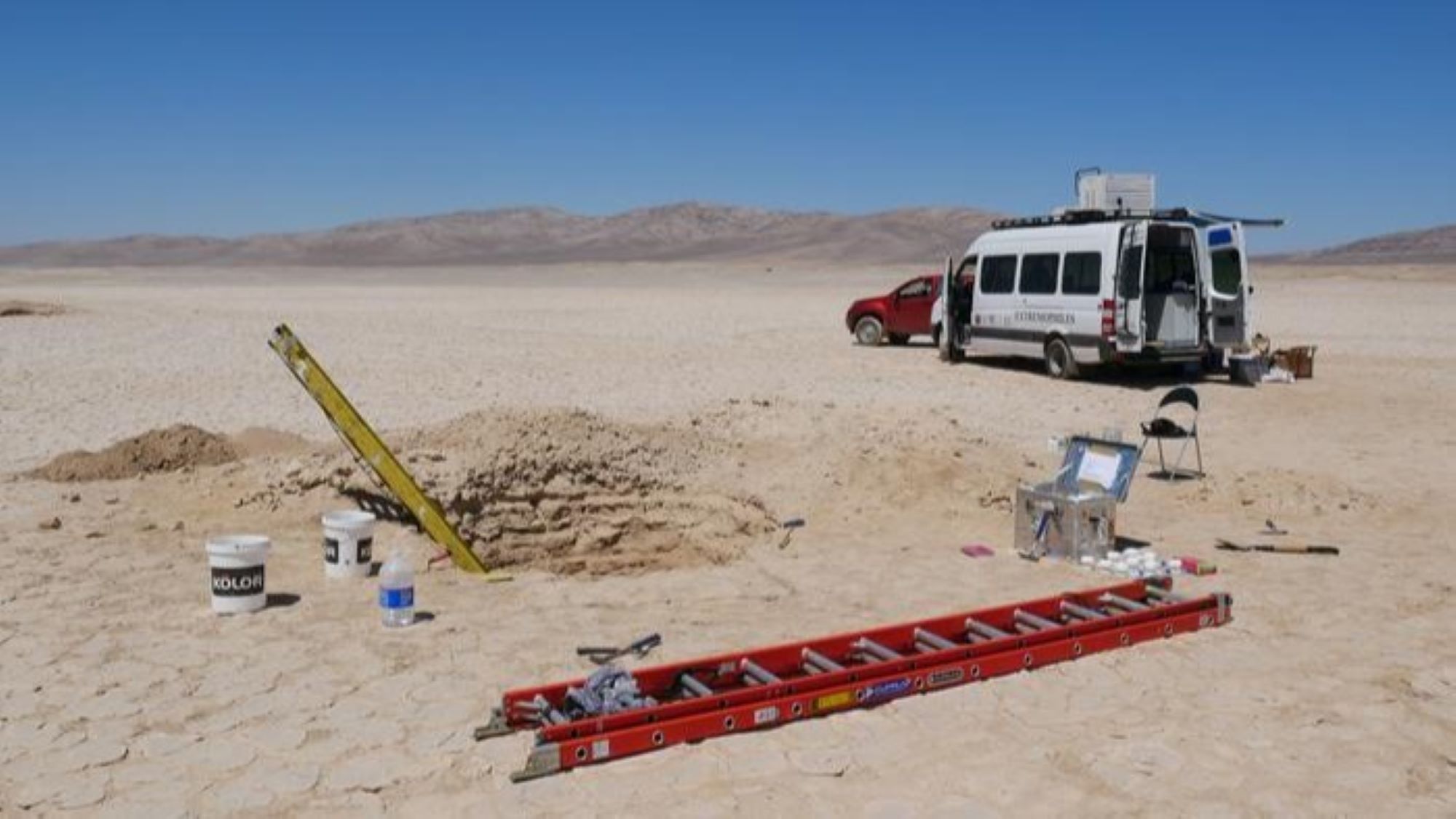 The study site in the Atacama Desert, pictured with a truck and van in the background and ladders and tools in the foreground