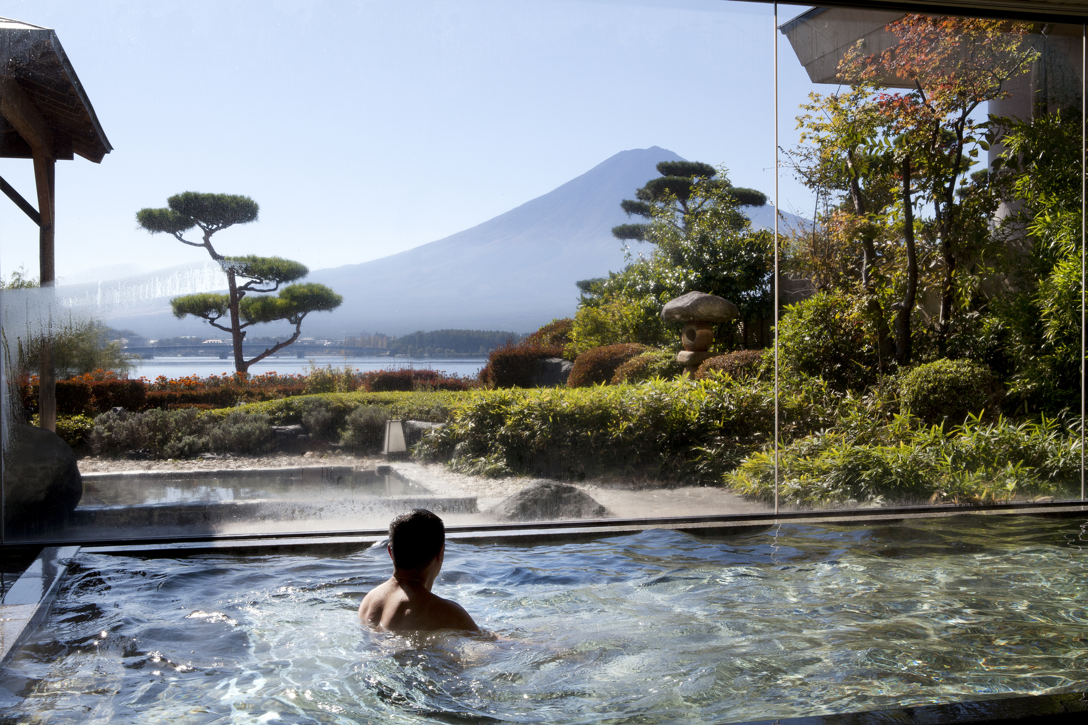 A man relaxes in a hot tub that has a view of Mt. Fuji in Japan.