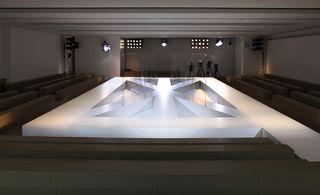 Catwalk featuring an outer rectangle and three intersecting paths running through it, with transparent Perspex screens placed in the middle of the set up, referencing the geometric elements of the collection.