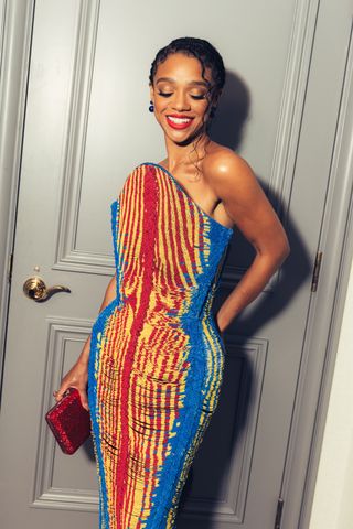 Tiffany Boone smiles in front of the door to her suite wearing a beaded Balmain dress for the Lion King Mufasa premiere