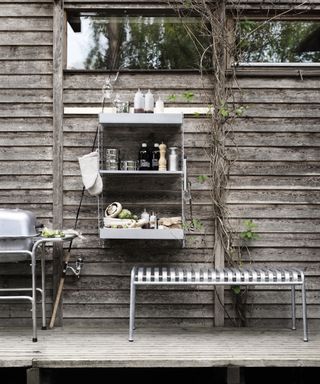Garden shelving mounted on a wood cladd outdoor wall next to a bbq