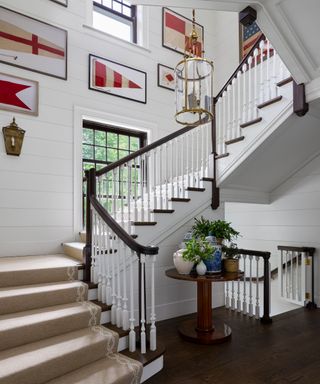 grand staircase with nautical flags on white walls