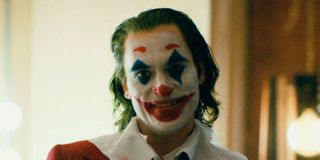 Joaquin Phoenix smiles in clown makeup in Joker