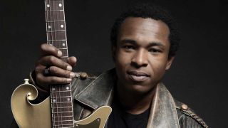 Solomon Hicks holding a guitar (studio portrait)