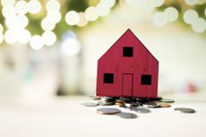 red house on pile of coins against a light background