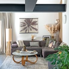 White living room with steel beams, grey sofa, marble coffee table and rattan lamp