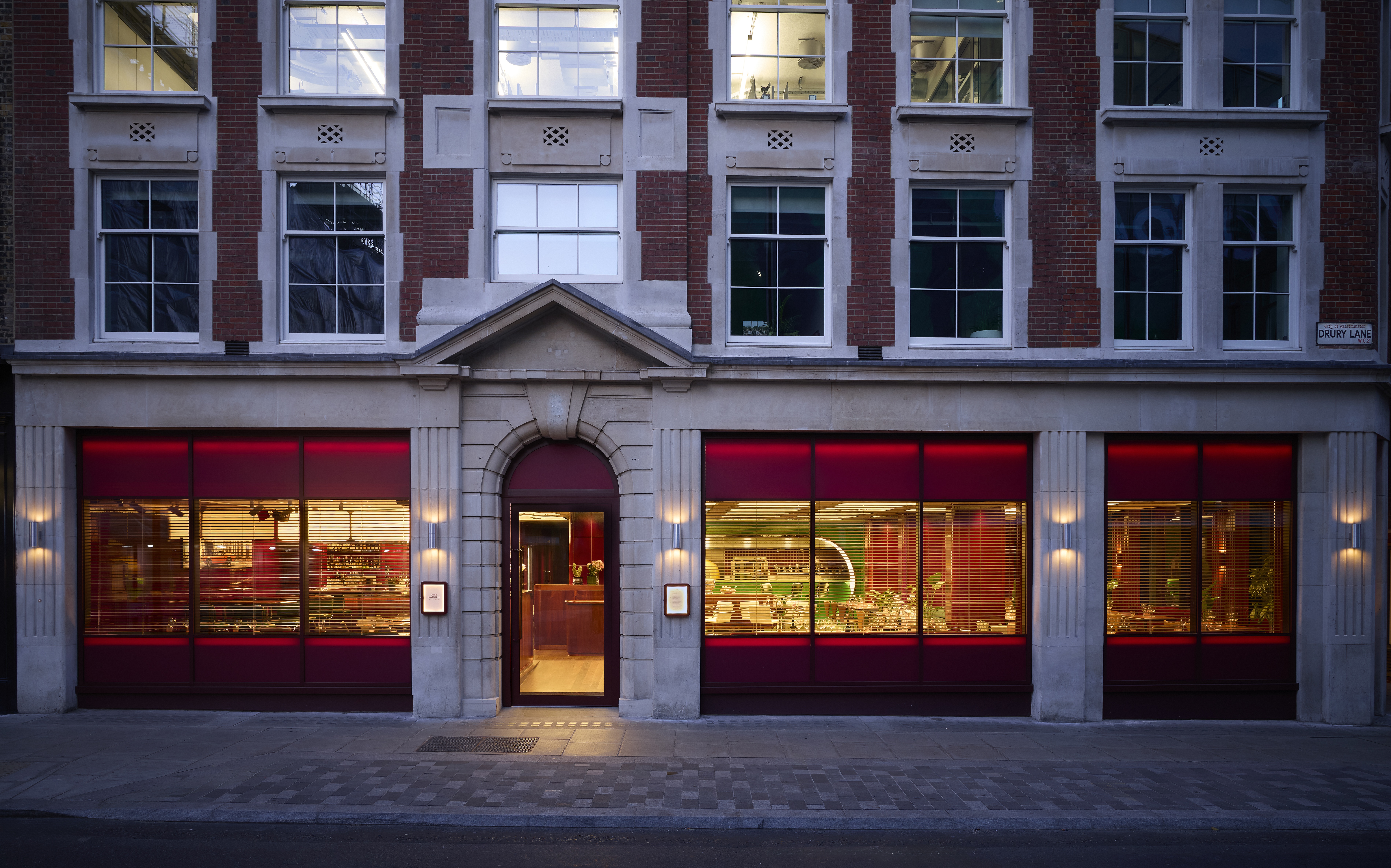 The exterior of a glamorous restaurant lets its warmth out onto an ornate, historical street.