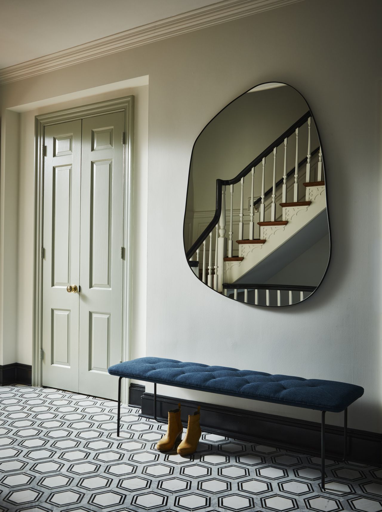 An entrance with blue-patterned tiles, black framed main door and cream walls
