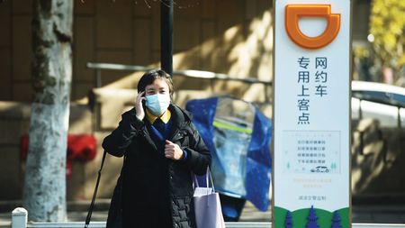 A woman walks by a signpost for Didi